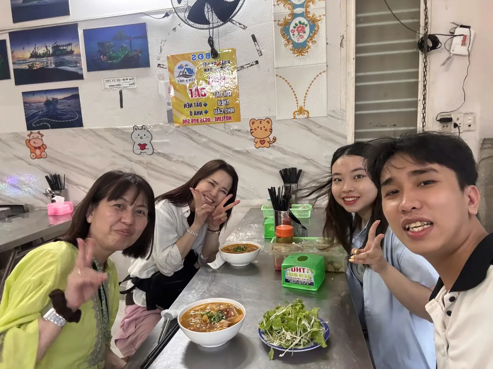 Guests with a bowl of mì Quảng turmeric noodles and fresh herbs at a Da Nang noodle shop