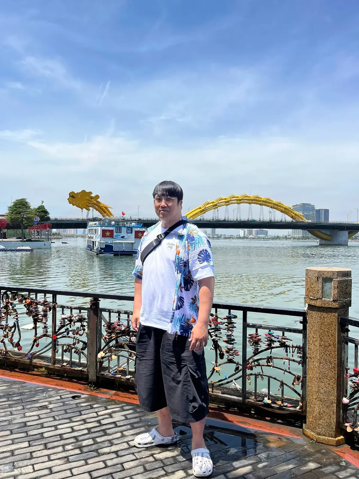 A traveller on the Han River promenade in Da Nang with the Dragon Bridge behind