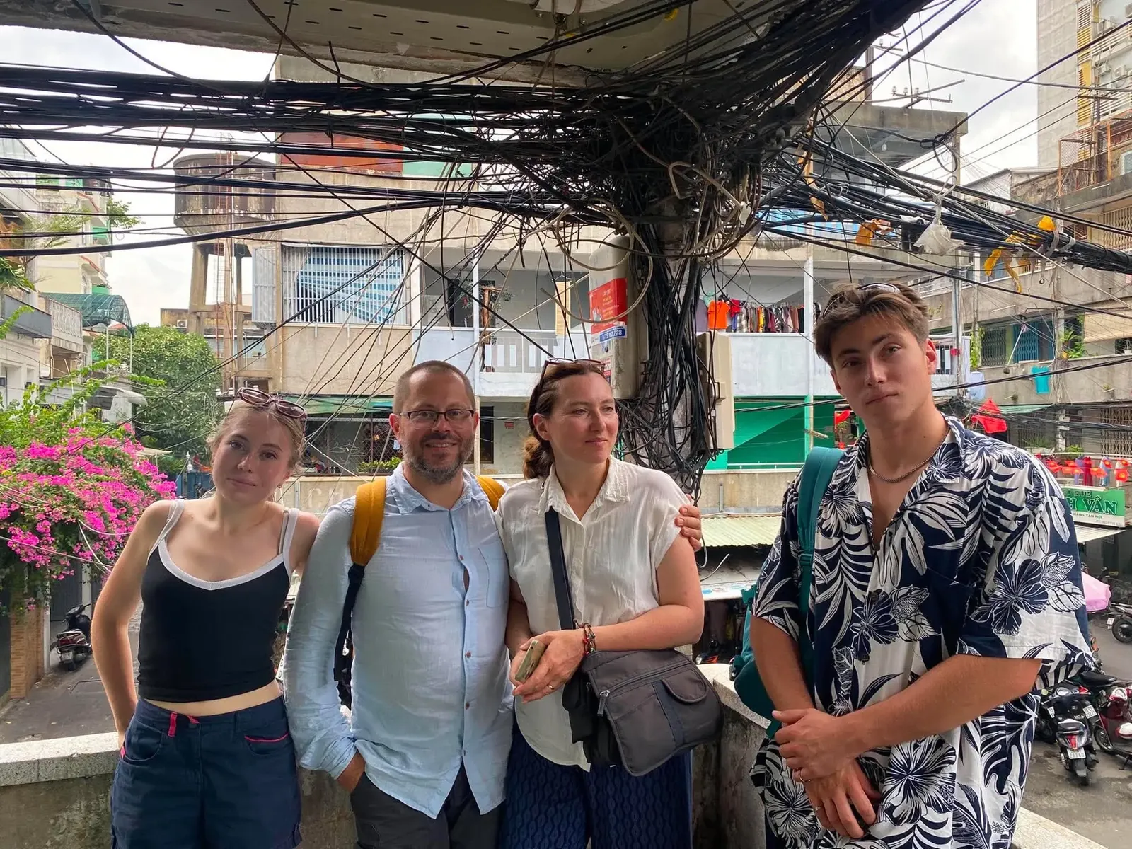 Four travellers on an old Saigon street under tangled power lines
